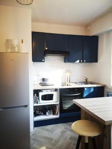 een keuken met blauwe kasten en een wit apparaat bij Cozy Woodland Oasis - Superbe appartement rénové, calme et lumineux - BEC in Bons