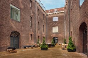 a brick building with tables and benches in a courtyard at Hotel Arsenaal Delft in Delft
