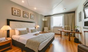サンパウロにあるペスターナ サンパウロの大きなベッドとデスクが備わるホテルルームです。