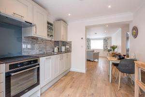 a kitchen with white cabinets and a dining room at Hattie's in Saxmundham