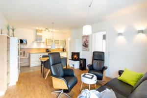 uma sala de estar com um sofá e cadeiras e uma cozinha em Quartier 7 App 04 em Ahlbeck