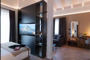 a hotel room with a bed and a couch and a television at 3T Boutique Hotel in Ivrea