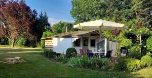 a small white house with an umbrella in a yard at Reinecke Fuchs in Bad Münder am Deister