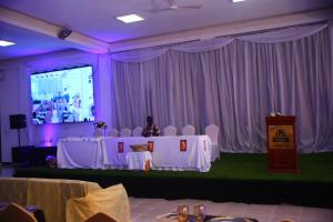 a room with a stage with white tables and chairs at Hoima Buffalo Hotel & Business Hub LTD in Hoima