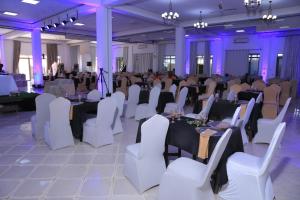 un salón de banquetes con mesas, sillas e iluminación púrpura en Hoima Buffalo Hotel & Business Hub LTD, en Hoima