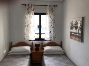 dwa łóżka pojedyncze w pokoju z oknem w obiekcie Stunning Apartment - Playamarina 2 Cabo Roig w mieście Orihuela Costa
