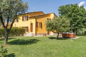 a yellow house with trees in a yard at Montenovo Country House in Ostra Vetere