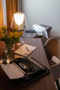 einen Schreibtisch mit einem Laptop auf einem Tisch mit Blumen in der Unterkunft 3T Boutique Hotel in Ivrea