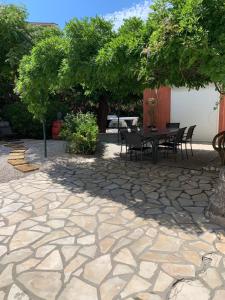 un patio con mesa y sillas bajo un árbol en Les dahlias appartement 4 personnes Jacuzzi Barbecue Jardin arboré Climatisé en Agde