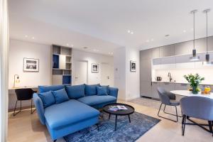ein Wohnzimmer mit einem blauen Sofa und einem Tisch in der Unterkunft #stayhere - Brand New & Ultra Modern 1BDR Upscale Neighbourhood Paupys in Vilnius