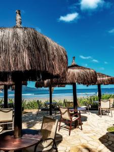 eine Gruppe von Stühlen und Sonnenschirmen am Strand in der Unterkunft Barequeçaba Praia Hotel in Barequeçaba