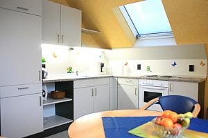 a kitchen with white cabinets and a table with a bowl of fruit at Ferienwohnung Anna in Wermelskirchen