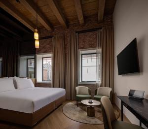 a hotel room with a bed and a desk and chairs at Hotel Arsenaal Delft in Delft