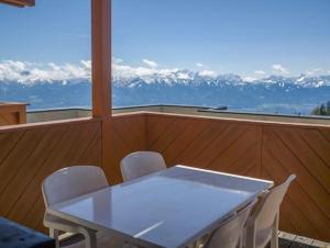 einen weißen Tisch und Stühle auf einem Balkon mit Bergblick in der Unterkunft LivGood Appartements Gerlitzen in Treffen