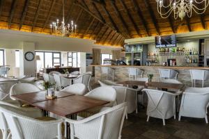 ein Restaurant mit Tischen und Stühlen und eine Bar in der Unterkunft Fynbos Golf and Country Estate in Eersterivierstrand