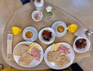 una mesa con platos de comida y tazas de zumo de naranja en Hotel Boutique Suite Generis, Premiado El hotel más acogedor de España, en Córdoba