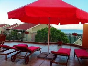 een rode parasol op een patio met stoelen bij Apartment Grotte Furci Siculo in Furci Siculo