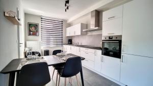a kitchen with white cabinets and a table with chairs at Appartement cosy et familial avec terrasse in Theux