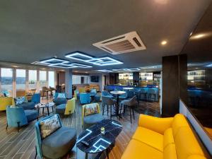 a restaurant with a yellow couch and tables and chairs at CHRISTEE SUITES HOTEL in Melaka