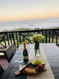 a table with a bottle of wine and a vase of grapes at 35 on Bondi South Africa in Shelly Beach