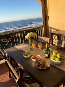 una mesa con comida y bebida en un balcón con vistas al océano en 35 on Bondi South Africa, en Shelly Beach