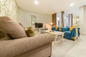 ein Wohnzimmer mit Sofa und Fernseher in der Unterkunft Holidays2Malaga Suites in Málaga