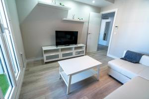 a living room with a white couch and a tv at Cabildo Spa 1 in Sanlúcar de Barrameda
