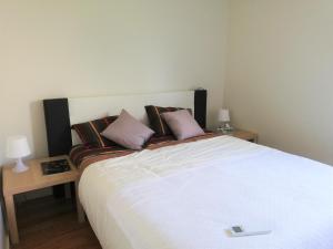um quarto com uma grande cama branca com almofadas em Station House em Guimarães