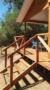 a wooden deck with a gazebo and a chair at Cabaña La Lechiguana in Maldonado