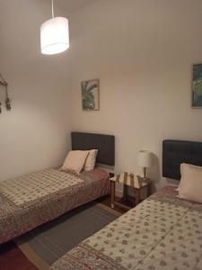 a room with two beds and a table and a lamp at Casa do Mocho II in Lisbon