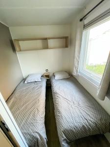 two beds in a small room with a window at Charmant Mobil-Home 6 pers in Narbonne