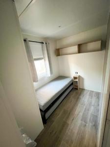 niewielka sypialnia z łóżkiem i oknem w obiekcie Charmant Mobil-Home 6 pers w mieście Narbona