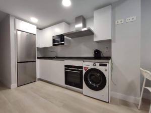 a kitchen with a washing machine and a refrigerator at Apartamento LA ESTACIÓN con terraza in Gijón