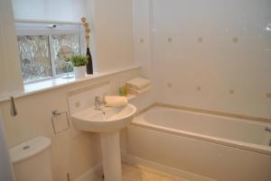 a white bathroom with a sink and a bath tub at Garfield Place Cosy 2-Bedroom Cottage Central Windsor with Parking in Windsor +22 photos
