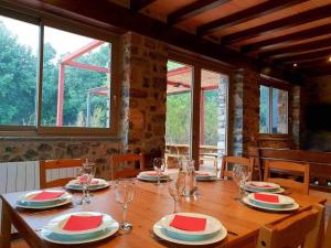 una mesa de madera con platos y copas de vino. en Casa en paraje natural único 25 pax, en Girona