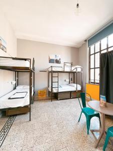 Cette chambre comprend 3 lits superposés, une table et des chaises. dans l'établissement Ostello Bello Napoli, à Naples