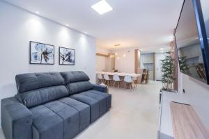 a living room with a couch and a dining room at Adra 106 - Apartamento no centro de Bombinhas - Rooftop com piscina e academia - À poucos metros da praia - (Consultar serviços de roupas de cama e banho) in Bombinhas