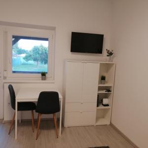 ein Wohnzimmer mit einem Tisch und einem TV an der Wand in der Unterkunft Werner Apartman in Mohács
