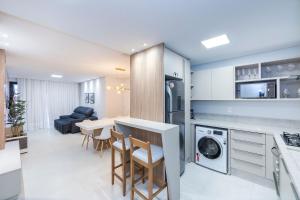 a kitchen and living room with a table and chairs at Adra 106 - Apartamento no centro de Bombinhas - Rooftop com piscina e academia - À poucos metros da praia - (Consultar serviços de roupas de cama e banho) in Bombinhas