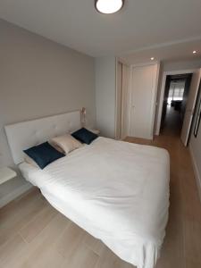 a white bed with blue pillows in a bedroom at Apartamento LA ESTACIÓN con terraza in Gijón
