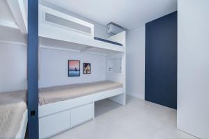 a bedroom with white walls and a bunk bed at Adra 106 - Apartamento no centro de Bombinhas - Rooftop com piscina e academia - À poucos metros da praia - (Consultar serviços de roupas de cama e banho) in Bombinhas +40 photos
