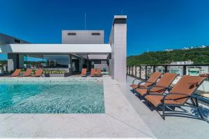 a pool on the roof of a building with lounge chairs at Adra 106 - Apartamento no centro de Bombinhas - Rooftop com piscina e academia - À poucos metros da praia - (Consultar serviços de roupas de cama e banho) in Bombinhas