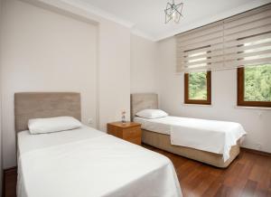 2 Betten in einem Schlafzimmer mit weißen Wänden und Holzböden in der Unterkunft Bengisu suite apart in Trabzon