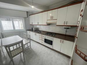 kuchnia z białymi szafkami, stołem i krzesłami w obiekcie Grupo Gontad Apartamento Cordobés, Ponteceso w mieście A Coruña