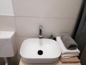 ein Bad mit einem Waschbecken, einem WC und Handtüchern in der Unterkunft Werner Apartman in Mohács