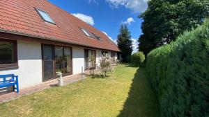 ein Haus mit rotem Dach und Hecke in der Unterkunft Hotel Pension Brilke Negast in Steinhagen