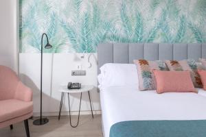 a bedroom with a bed and a pink chair at Hotel Cristina by Tigotan Las Palmas - Adults Only in Las Palmas de Gran Canaria