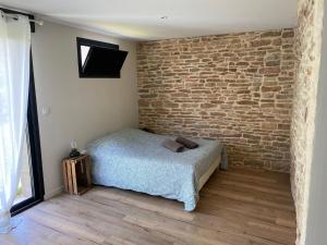 Un dormitorio con una pared de ladrillo y una cama en Appartement tout confort et spacieux en campagne bourguignonne, en Mancey
