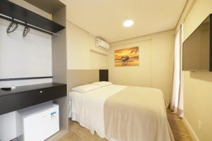 a bedroom with a white bed and a flat screen tv at Easy Suites Natal in Natal