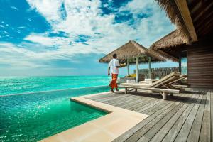a man standing on a dock next to the ocean at COMO Maalifushi - Partner Travels FREE for 7 Nights or More in Maalifushi